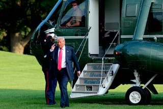 US president Donald Trump lifts his hand in a salute as he exits Marine One on the South Lawn of the White House